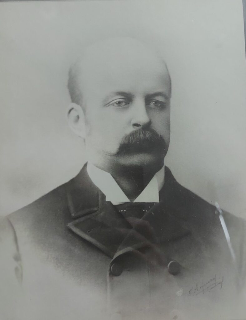 Vintage head and shoulders photograph of man with bushy mustache in a suit