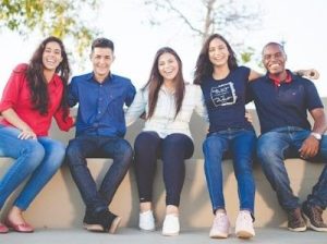 5 young people sitting on a wall and smiling